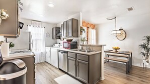 Une cuisine moderne dotée d’appareils électroménagers en acier inoxydable, d’un four encastré et d’un coin repas avec une banquette.