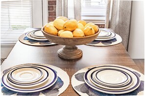 Une table en bois sur laquelle se trouve un saladier rempli de citrons et des assiettes aux motifs bleus et blancs.