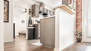Une cuisine moderne avec un plancher en bois, un four encastré et un mur d’accent en briques.