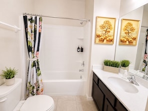 Un bagno con vasca, water, lavandino e due quadri appesi al muro.