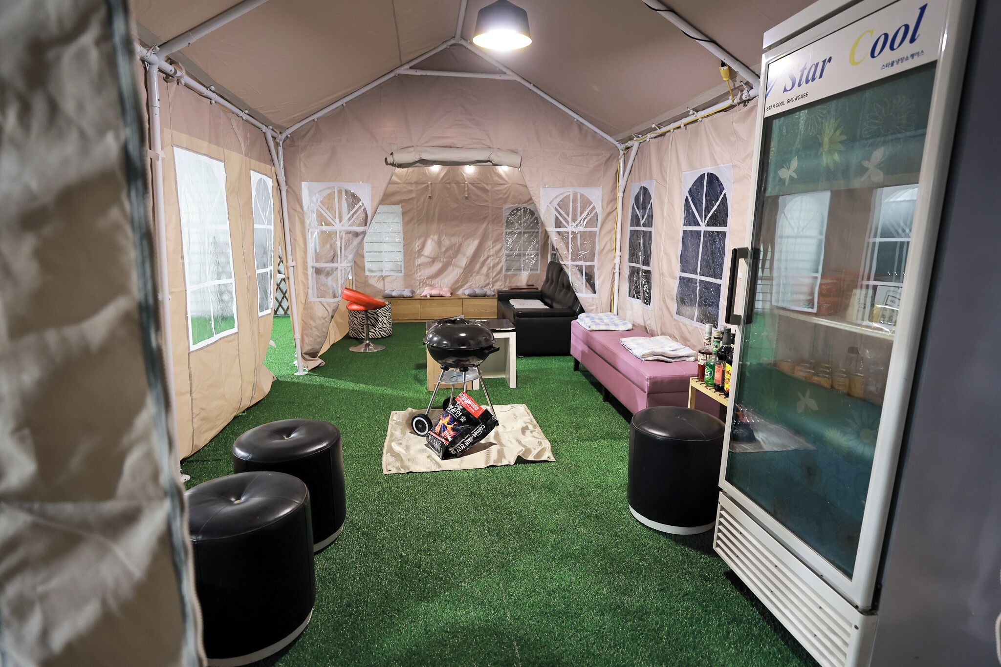 Una habitación con carpa, una kitchenette, un sofá y un ventanal grande.