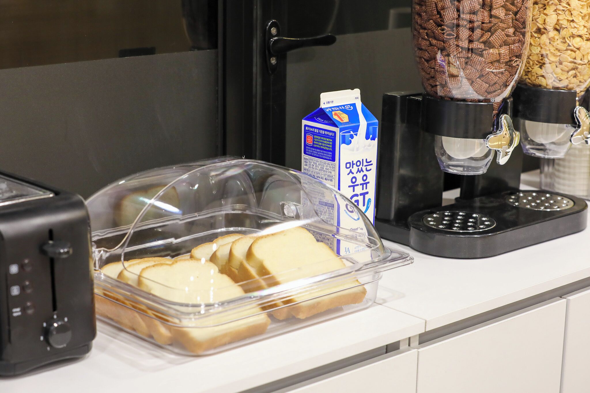 Ein Frühstücksbuffet mit Toaster, Milchkarton und Getreideausgabe.