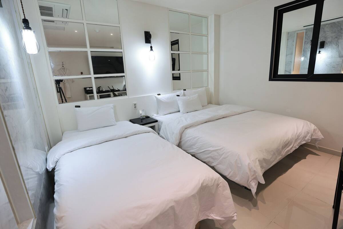 Een hotelkamer met twee bedden, een kledingkast, een spiegel en een bureau met lamp.