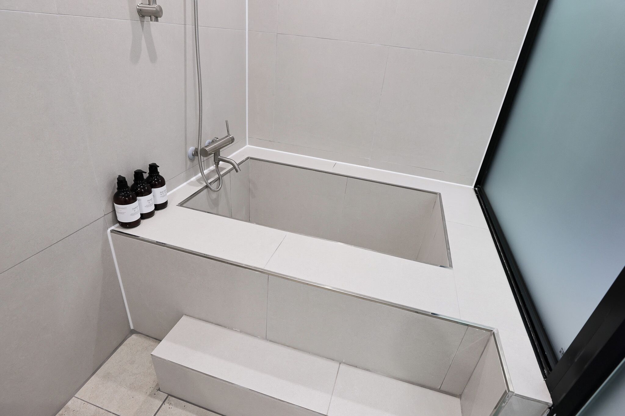 Un baño moderno con una bañera, ducha y un juego de artículos de tocador al borde.