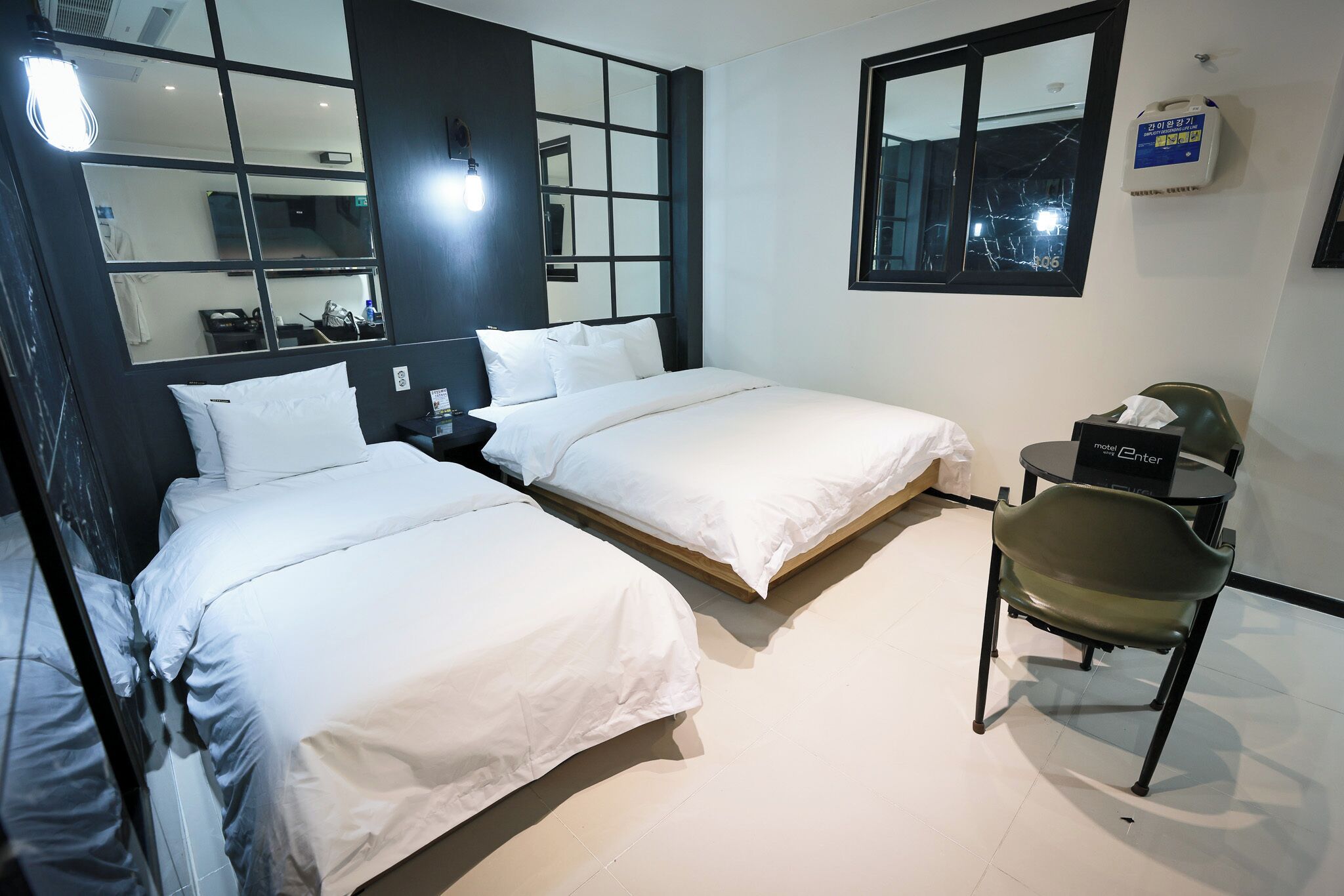 Habitació d'hotel amb dos llits, una cadira, una taula de nit i una finestra que ofereix vista a l'exterior.