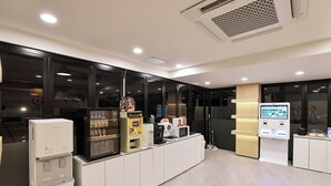 Un hall d’hôtel moderne doté d’un kiosque en libre-service, d’une machine à café et d’un distributeur de boissons.