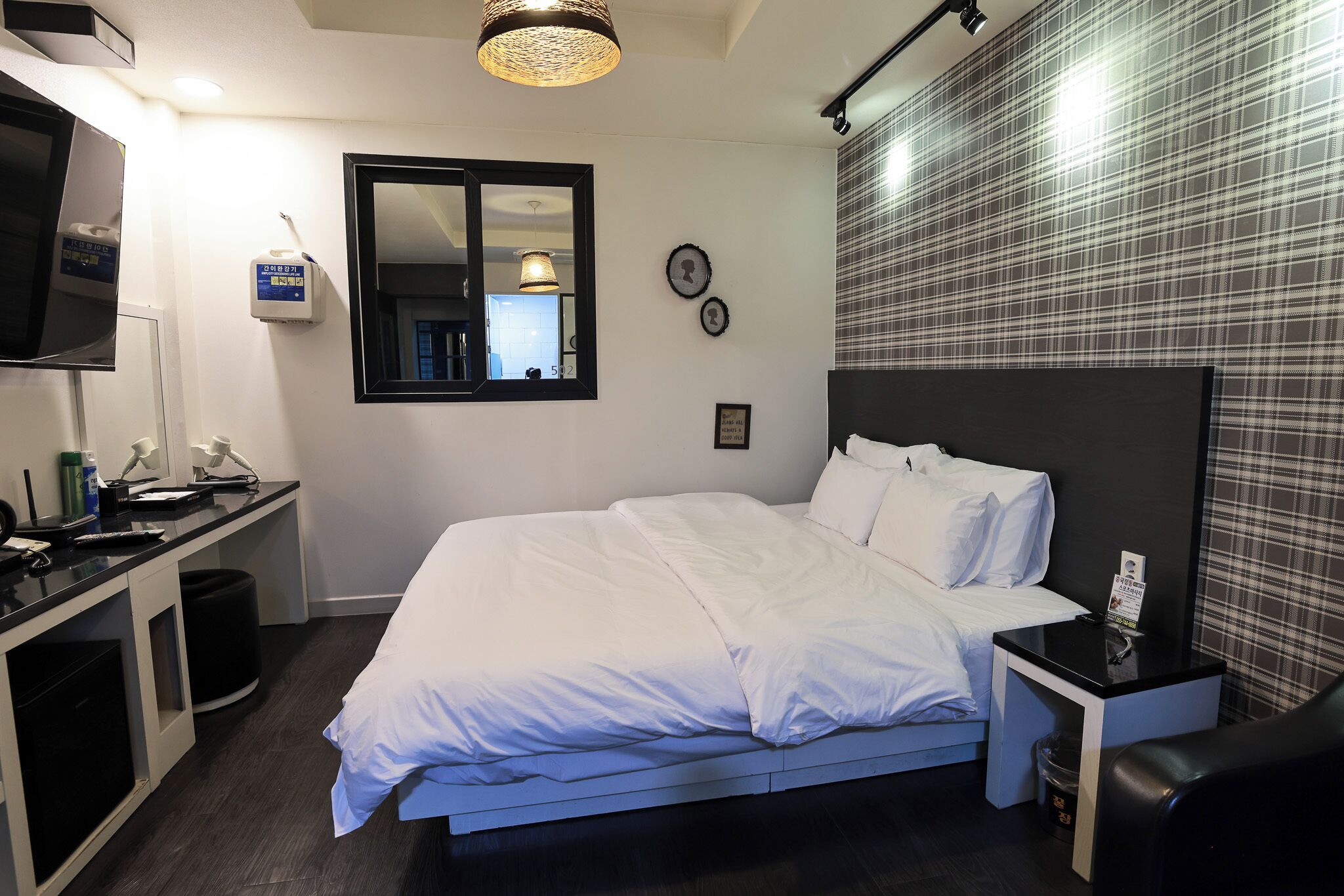 A hotel room with a bed, bedside table, TV, and a mirror.