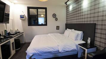 A hotel room with a bed, bedside table, TV, and a mirror.