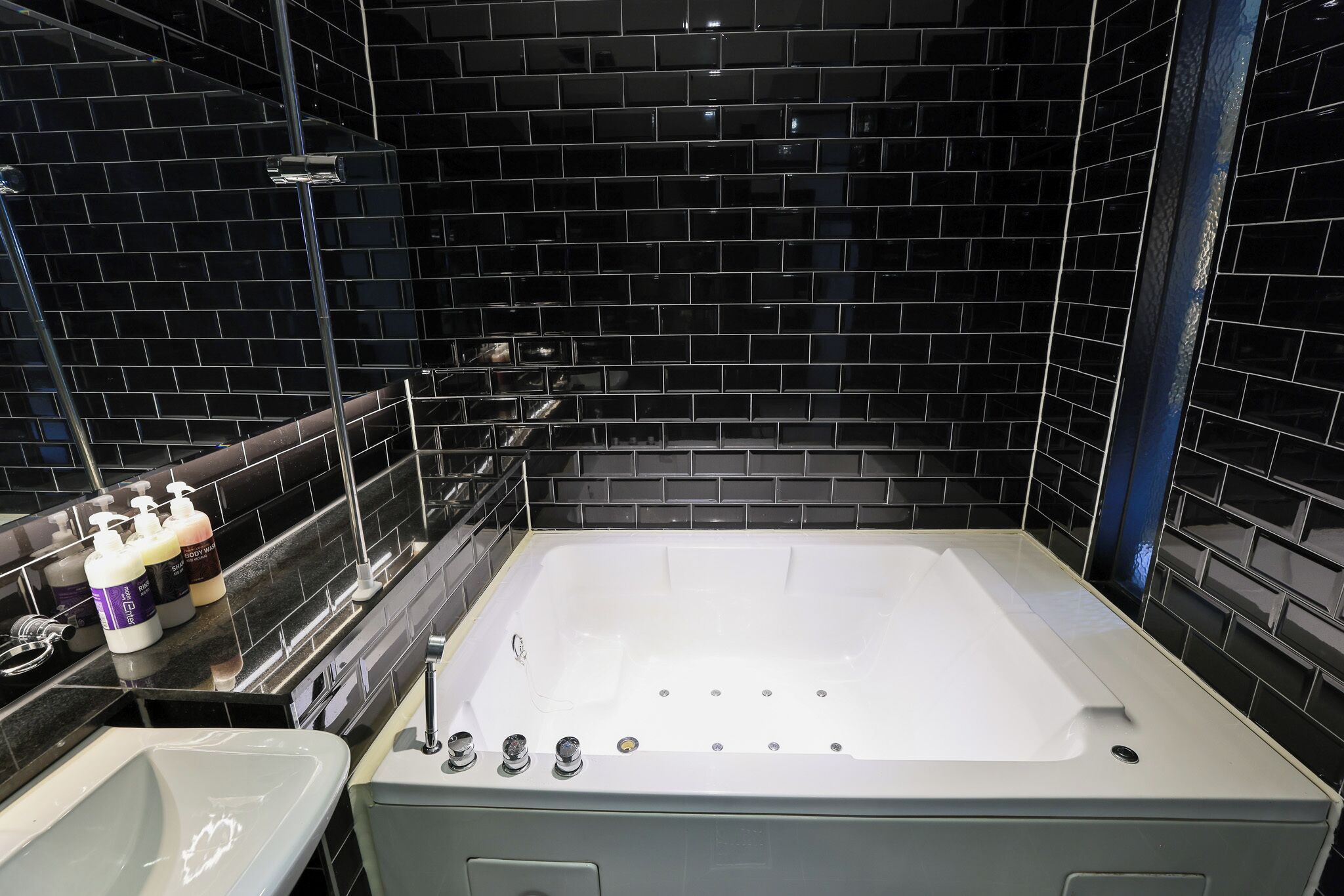 A modern bathroom with a large bathtub, a sink, and a mirror.