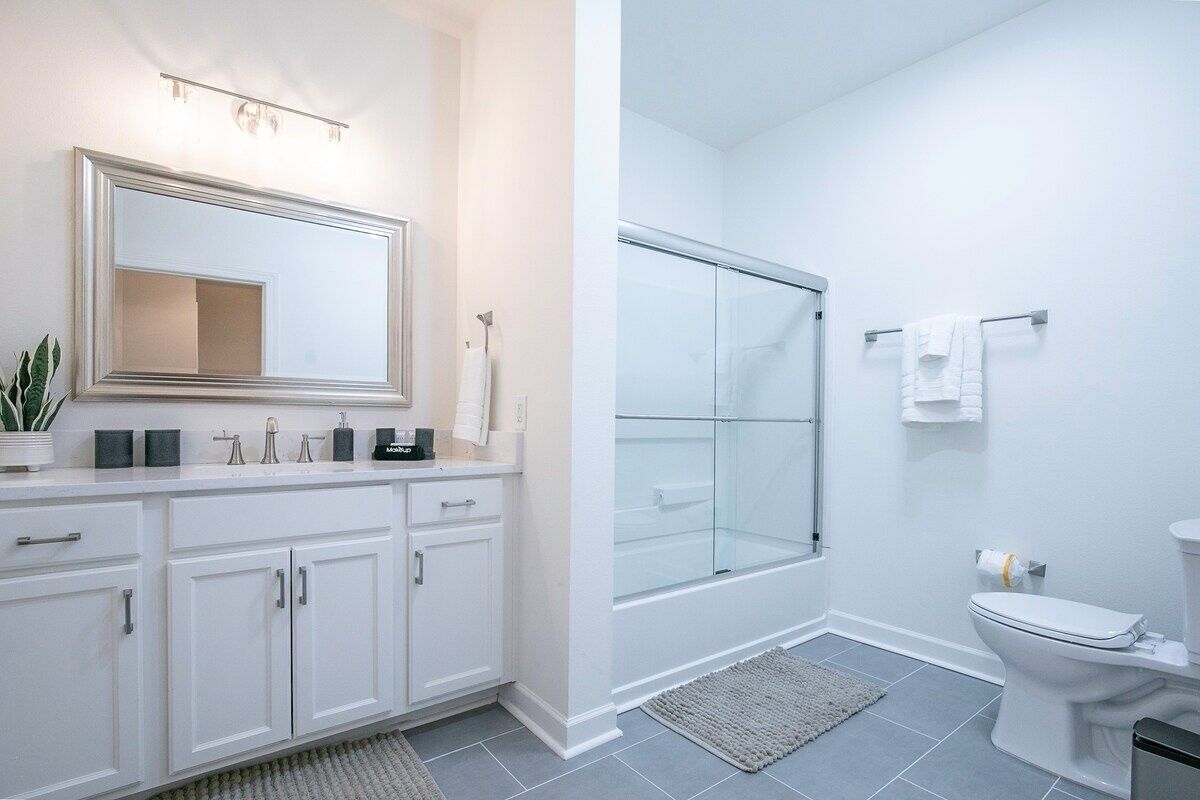 A modern bathroom with a white vanity, a glass shower enclosure, and a toilet.