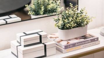 Un escritorio blanco con una pequeña planta en maceta, una pila de cajas blancas y un libro titulado 'Down to Earth' de Myquillyn Smith.