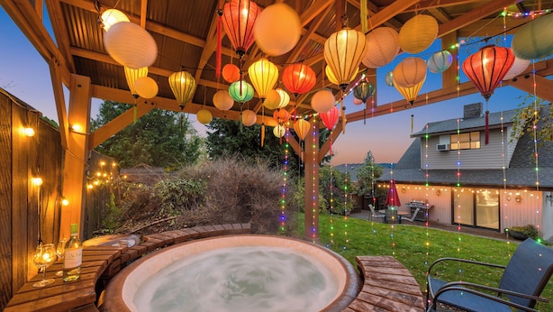 Ein Whirlpool unter einer Holzpergola mit Lichterketten und Papierlampen.