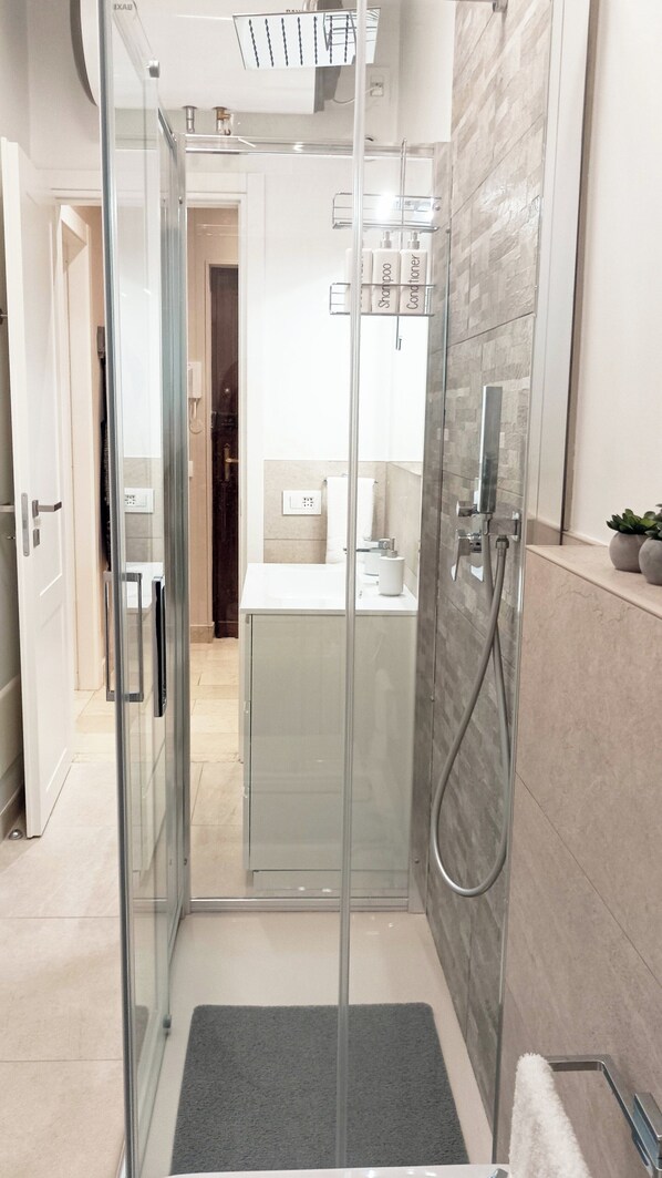 Un baño moderno con ducha de vidrio, lavamanos blanco y espejo.