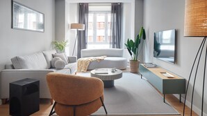 A modern living room with a sofa, armchair, coffee table, and TV. - Negua by FeelFree Rentals (San Sebastian)