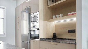 A modern kitchen with built-in appliances, wooden shelves, and a marble countertop. - Negua by FeelFree Rentals (San Sebastian)