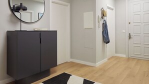A modern hallway with a dark grey cabinet, a round mirror, and a white door. - Negua by FeelFree Rentals (San Sebastian)