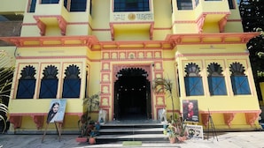 A multi-story building with a traditional architectural style, featuring a central entrance with steps leading up to it. - Roop Mahal Homestay (Udaipur)