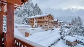 Een houten chalet met meerdere balkons, omgeven door met sneeuw bedekte bomen en een bergachtig landschap.