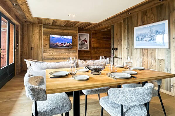 Un comedor con una mesa de madera dispuesta para seis personas, rodeada de sillas tapizadas.