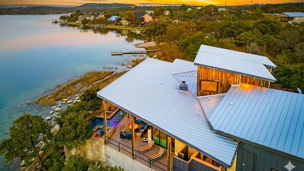 A lakeside property with a pool, outdoor seating, and a view of the water.