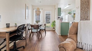 Una cocina moderna con piso de madera, un comedor con mesa y sillas de madera, y una zona de estar acogedora con un sofá acolchado.