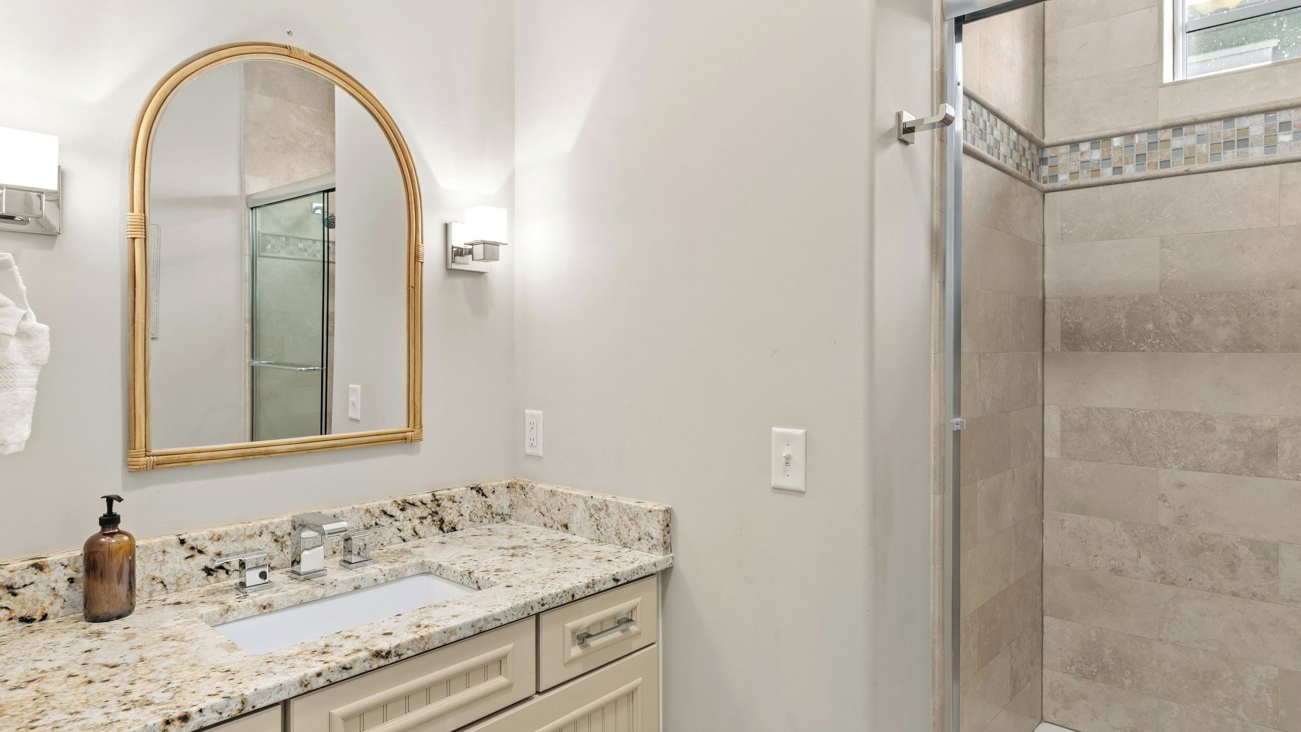 Une salle de bain avec un lavabo en marbre, un grand miroir et un espace douche.