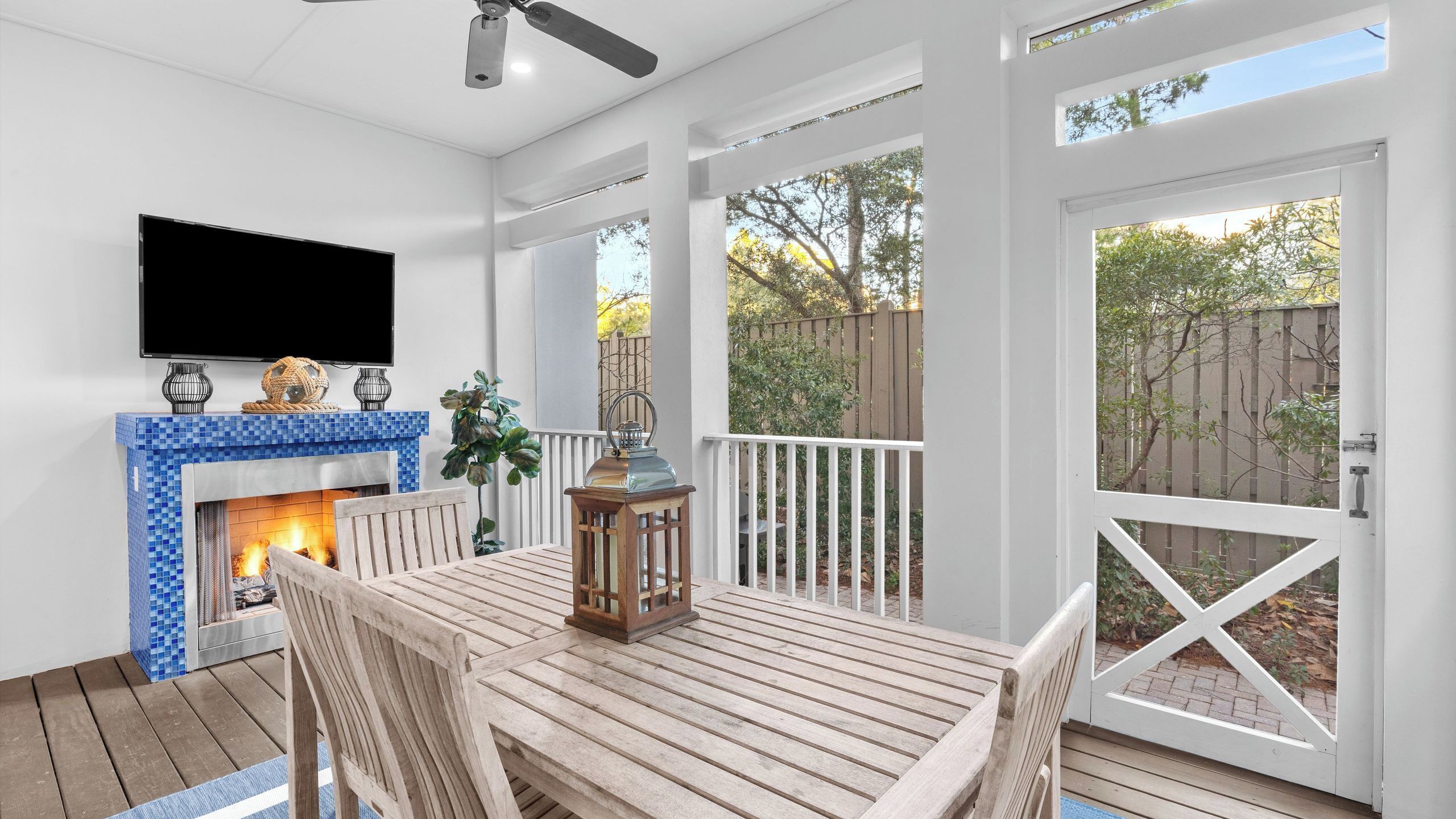 A covered patio with a fireplace, a table, chairs, and a TV mounted on the wall.