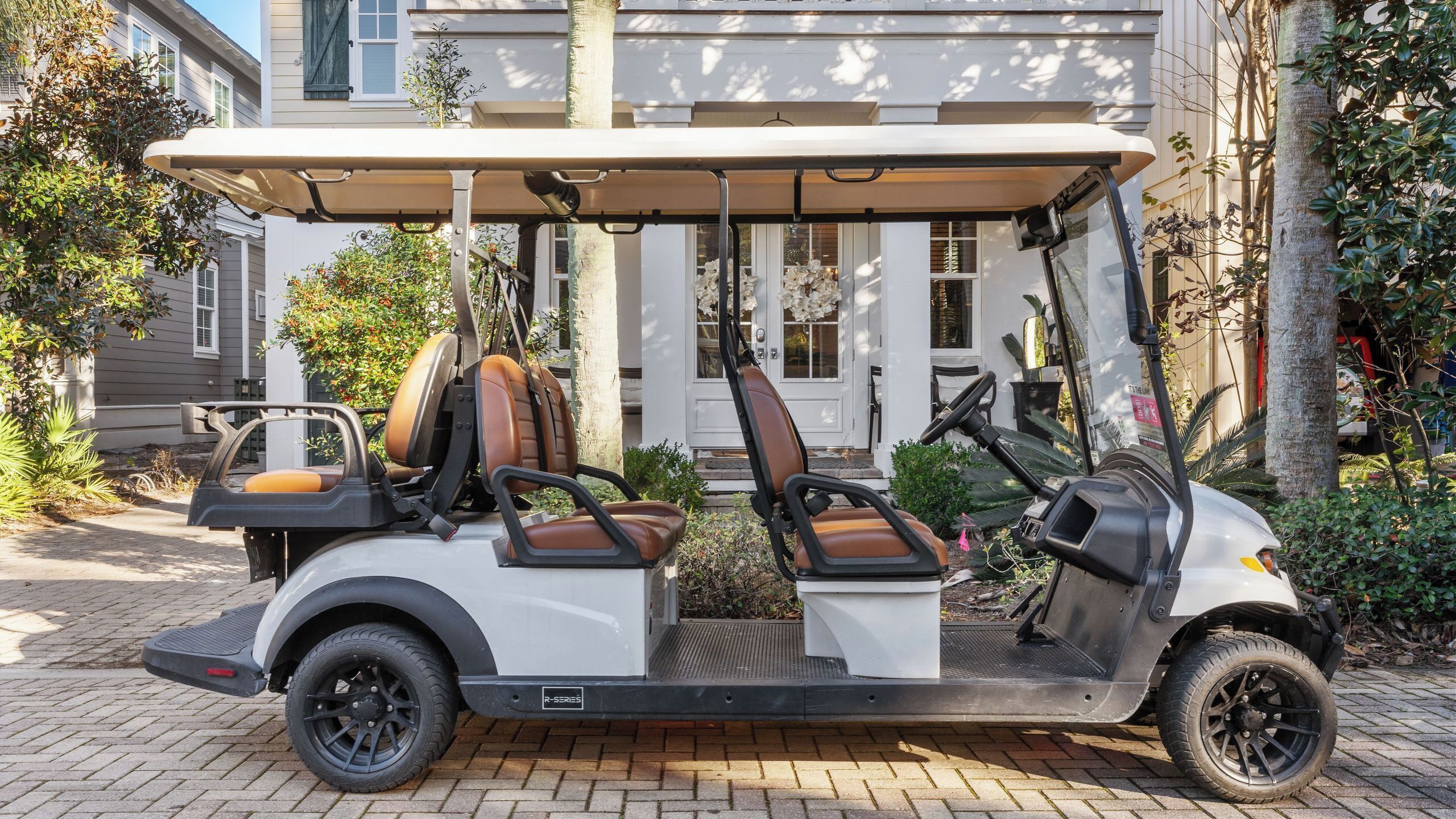 A golf cart parked in front of a building with a covered seating area and a driver's seat.