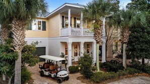 A two-story house with a porch, palm trees, and a golf cart parked in front. - Seagrove Gardens Mins to the Beach, Santa Rosa Retreat w/ A+ Design (Santa Rosa Beach)