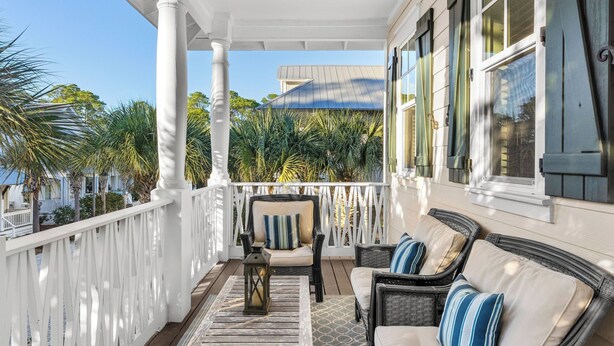 A covered porch with white railings, wicker furniture, and a view of a house and palm trees. - Seagrove Gardens Mins to the Beach, Santa Rosa Retreat w/ A+ Design (Santa Rosa Beach)