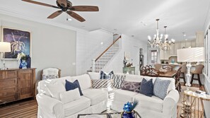 A spacious living room with a white sofa, a wooden coffee table, and a ceiling fan. - Seagrove Gardens Mins to the Beach, Santa Rosa Retreat w/ A+ Design (Santa Rosa Beach)