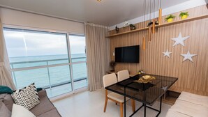 Una sala de estar moderna con una mesa de vidrio, un sofá y un televisor montado en la pared.