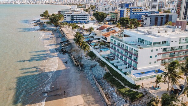 Un hotel frente al mar con varias plantas, una piscina y ubicación en la playa.