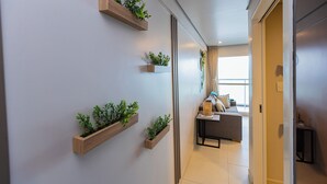 Un pasillo con macetas de madera en la pared, un sofá con cojines y una puerta que da a otra habitación.