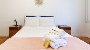 A neatly made bed with white linens and a pink blanket, a wall-mounted star decoration, and a small wooden nightstand with a lamp. - Refuge in Copacabana 5min From the Beach Nsc1102 (Rio de Janeiro)