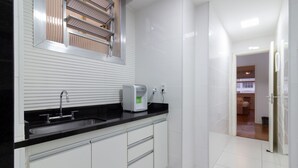 A modern kitchen with a black countertop, white cabinets, and a built-in sink. - Refuge in Copacabana 5min From the Beach Nsc1102 (Rio de Janeiro)