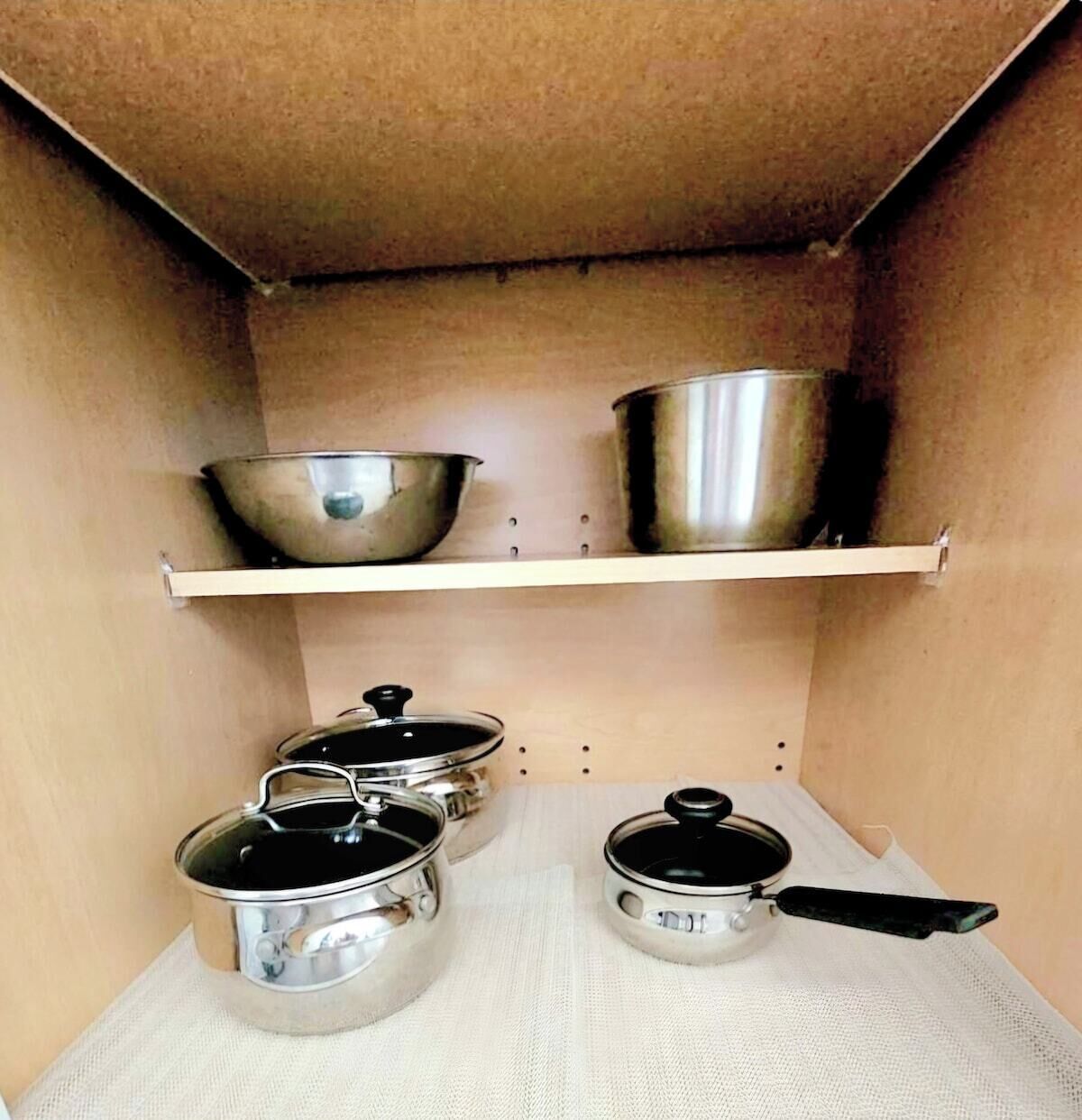 Una rebosteria de cuina amb vaixella d'acer inoxidable als prestatges i una taulella.