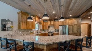 A spacious kitchen with a large island, wooden cabinets, and hanging pendant lights. - 20+ Guests-20 Minutes to Yellowstone-Hot Tub-Family Reunions-Fly Fishing (Island Park)