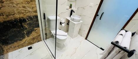 A modern bathroom with a glass-enclosed shower, a toilet, a sink, and a towel rack.