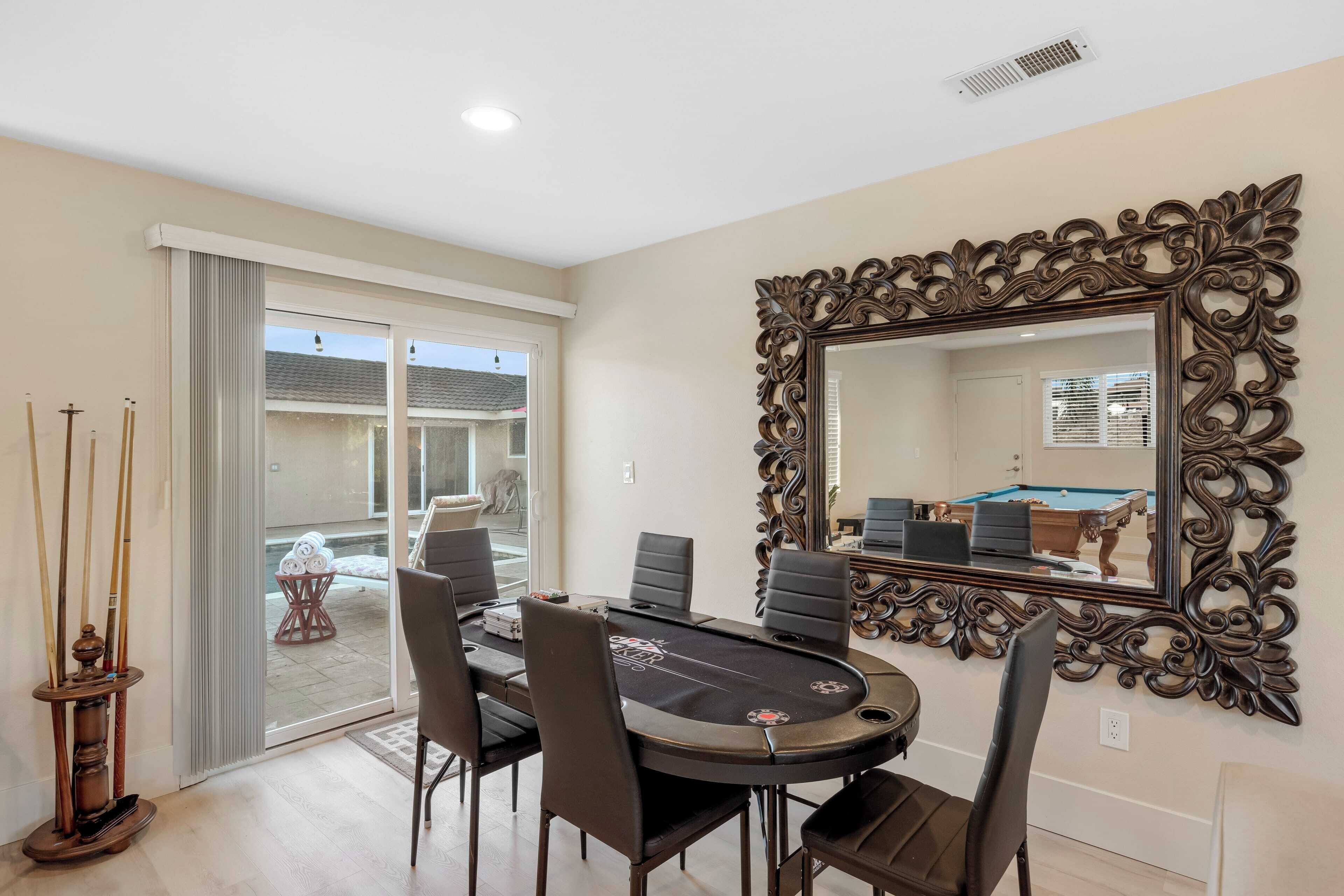 A billiards room with a pool table, chairs, and a large ornate mirror.