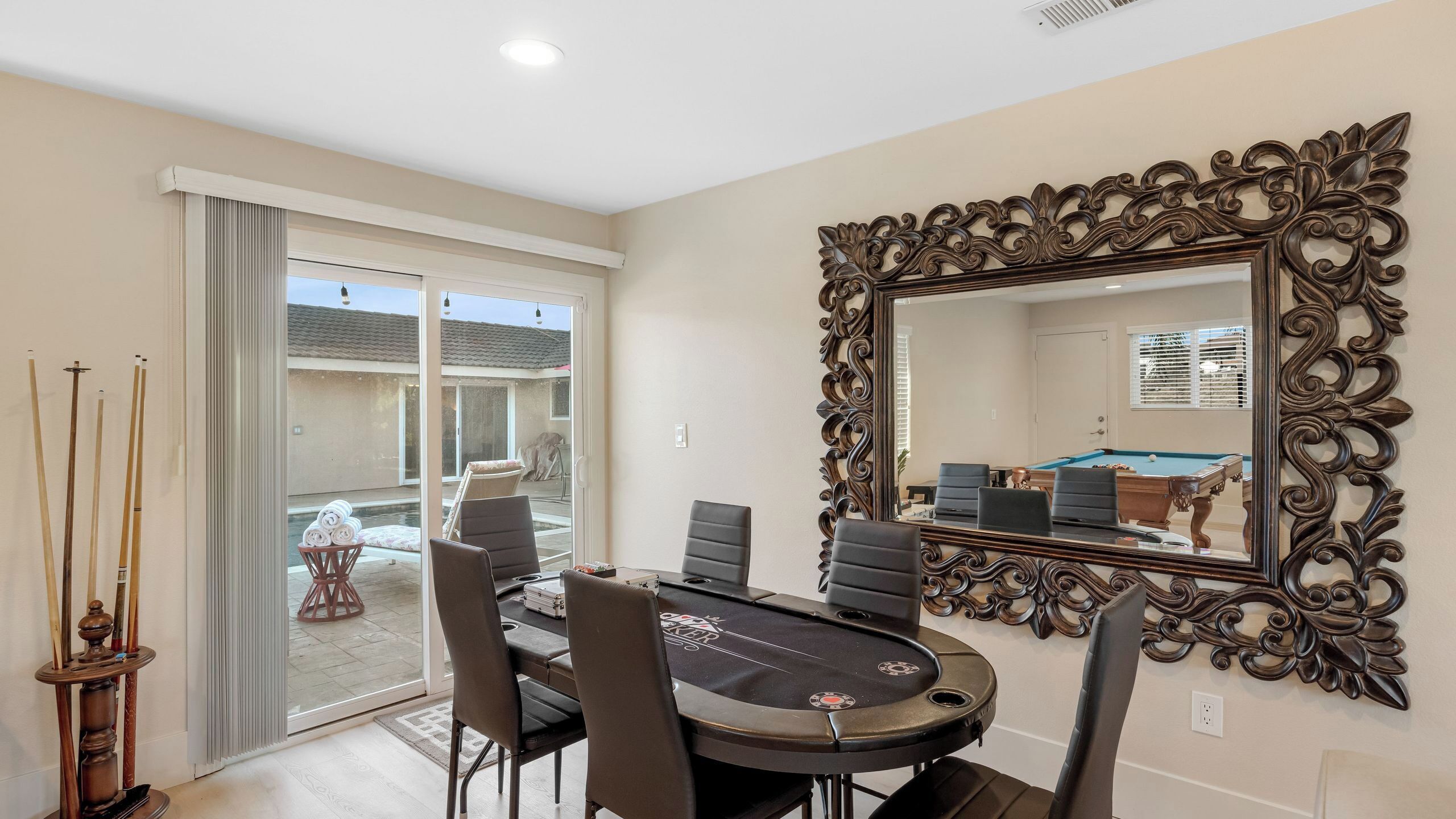 Un espace repas comprenant une table de billard, des chaises et un grand miroir décoratif.