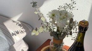 Une table en bois, une bouteille de vin, un bocal en verre rempli de fleurs et une bougie.
