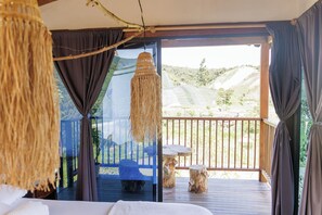 A room with a large window, a hanging light fixture, and a view of a deck and landscape. - MONTANA ECO HOTEL (El Santuario)