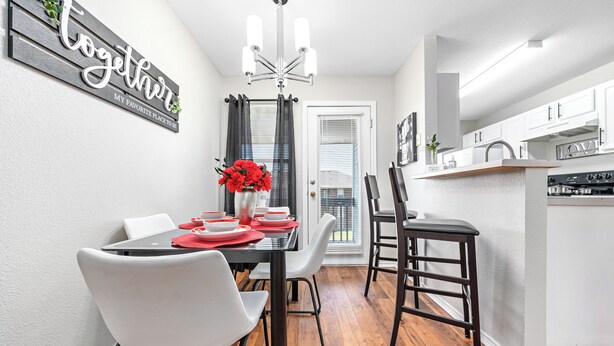 A modern dining area with a wooden table, white chairs, and a chandelier. - Charming 2-bedroom apartment with WiFi, AC in Killeen (Killeen)