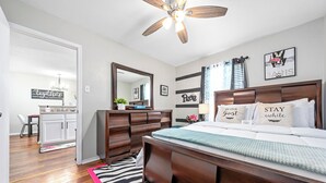 A bedroom with a wooden bed, a ceiling fan, a dresser, a mirror, and a desk with a chair. - Charming 2-bedroom apartment with WiFi, AC in Killeen (Killeen)