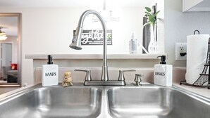 A modern kitchen with a double sink, two soap dispensers labeled 'HANDS' and 'DISHES', a vase with flowers, and a towel rack. - Charming 2-bedroom apartment with WiFi, AC in Killeen (Killeen)