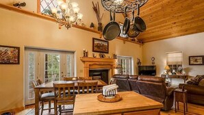 A cozy living room with a fireplace, wooden furniture, and a chandelier.