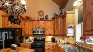 A kitchen with wooden cabinets, a stainless steel refrigerator, a microwave, a stove, and a sink.