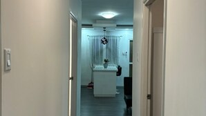 Een smalle gang met een keuken aan het einde, uitgevoerd in een modern design met een donker houten vloer en witte muren.
