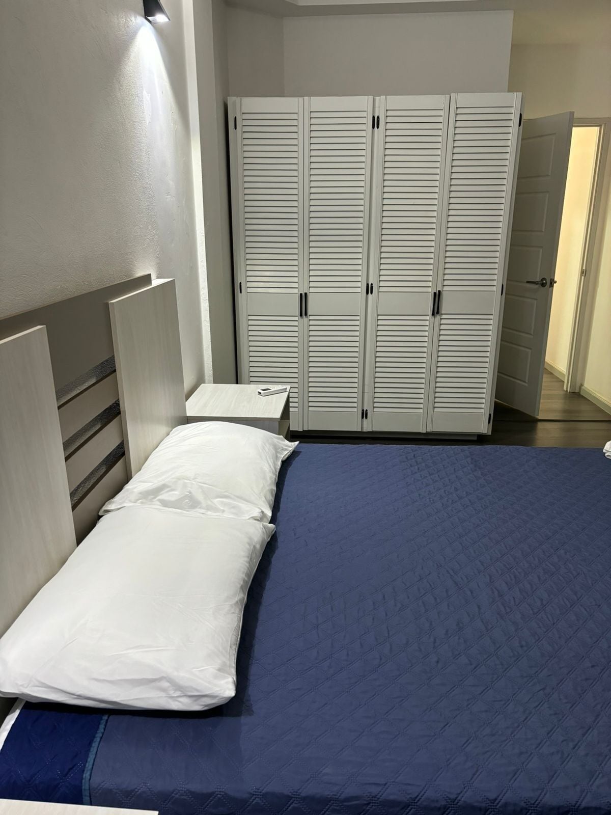 A bedroom with a bed, a nightstand, and a wardrobe.